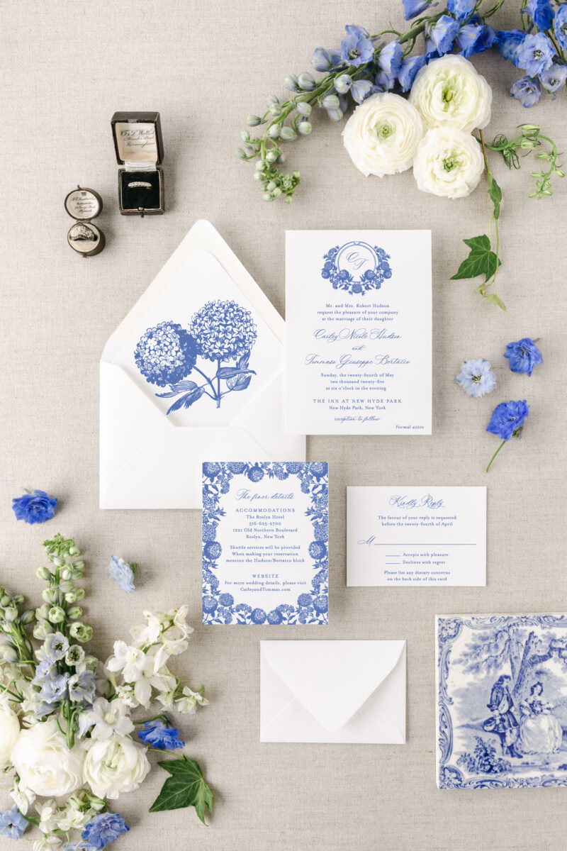 Blue wedding invitation suite featuring blue hydrangeas, a monogram crest, and envelope liner with hydrangea drawings or illustrations.