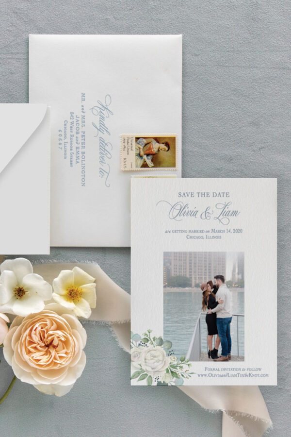 Picture save the date with watercolor eucalyptus and ivory and white roses and addressed envelopes with pretty wedding flowers.